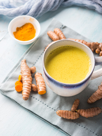 Golden turmeric coconut milk drink in mug on pastel background. Healthy remedy for sour throat and inflammationの写真素材