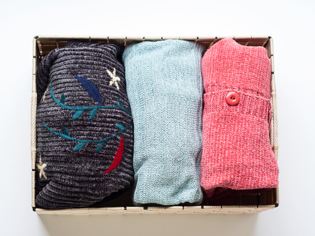 Pastel color womans clothes folded in a box on white background. Organising closet conceptの写真素材