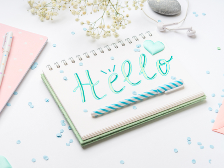 Spring girls items flat lay on white. Hello word written on notebook page in aquamarine colorの写真素材