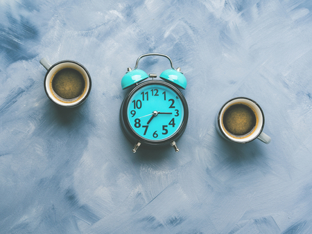 Two coffee cups and alarm clock on sky blue painted background. Minimal flat layの写真素材