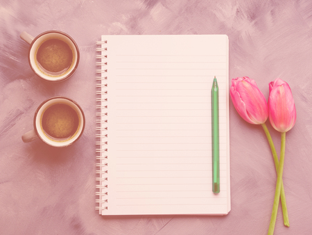 Two coffee cups and blank notepad page with pen and tulips on sky blue painted background. Minimal flat layの写真素材