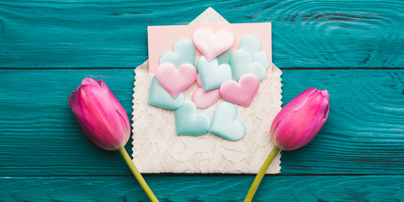 Envelope with pastel color hearts and pink tulip. Valentines day concept on dark wooden emerald green background.の写真素材