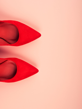 Monochrome pink background with red womans high heels shoes. Fashion background with copy space. Flat layの写真素材