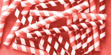 Red and black striped straws background. Party cocktail concept. Pink coral tone