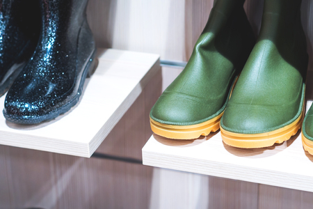 Black and green rubber boots on a shelf of a fast fashion store.