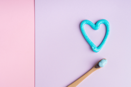 Toothbrush and toothpaste heart on pastel pink and purple background. Personal dental hygiene conceptの写真素材