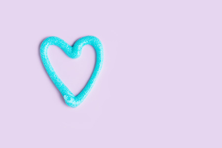 Blue heart made with toothpaste on violet purple background. Personal dental hygiene concept