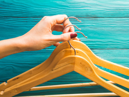 Wooden hangers with no clothes on green wooden background. Clothing storage, sale shopping concept