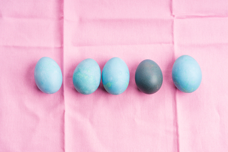 Colorful blue boiled easter eggs in a nest on pastel pink background. Flat layの写真素材