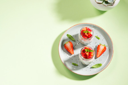 Yogurt granola parfait with strawberries and chia seeds. Healthy delicious dessert for breakfast. Mint green bright spring summer backgroundの写真素材