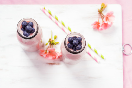 Strawberry banana smoothie topped with blueberries on pink background.の写真素材