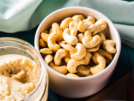 Home made cashew butter in a glass jar on green wooden table. Healthy plant food.の写真素材
