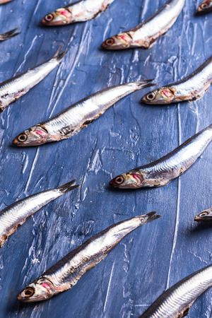 Fish isometric pattern. Fresh anchovies on blue sea effect background. Trendy food conceptの写真素材
