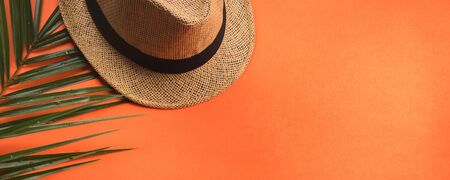 Vacation on the beach. Flat lay on orange coral background. Fern and straw hat. Banner.の写真素材