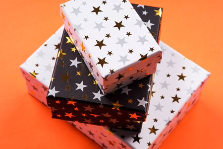 Stacked gift boxes with golden stars on orange background. Giving presents concept.の写真素材