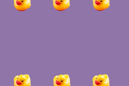 Yellow glamour rubber ducks with red lips pattern frame on purple background.