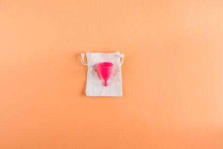 Pink menstrual cup with cotton bag, zero waste concept on orange background. Flat lay with copy spaceの写真素材