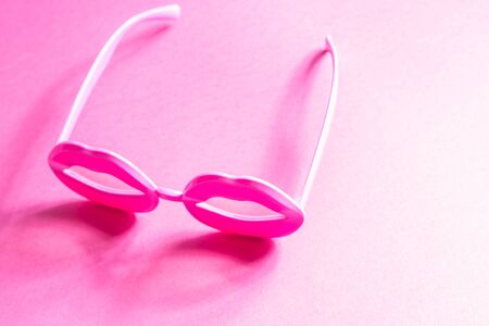 Pink funky lip shape glasses on neon monochrome. Pop art item composition.の写真素材