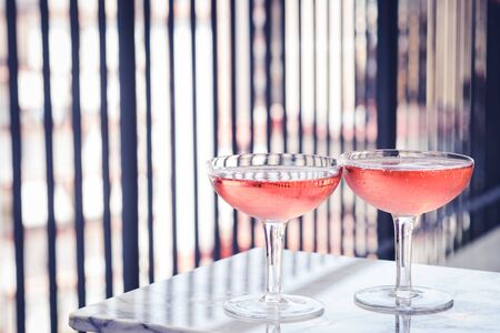 Two crystal stemmed glasses with rose wine on marble table outdoors in a cafe. Aperitif and relax timeの写真素材