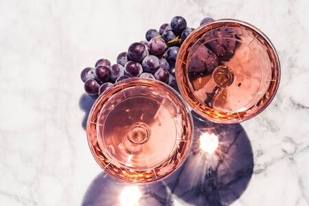 Two crystal stemmed glasses with rose wine on marble table outdoors in a cafe. Aperitif and relax timeの写真素材