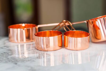 Copper measuring cups on marble table in the kitchen. Ready to cook or bulk food purchase conceptの写真素材
