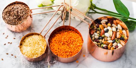 Copper measuring cups on marble table with beans and cereals in the kitchen. Cooking or bulk food purchase conceptの写真素材