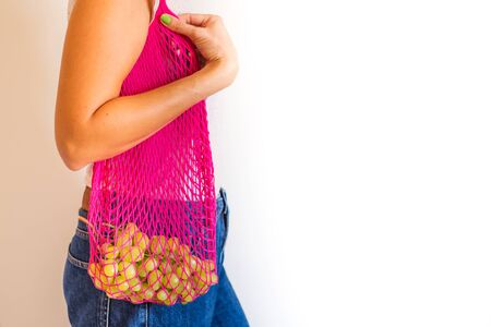 Zero waste concept. Young woman with pink reusable mesh shopping bag full of fresh grapes. Plastic free lifestyleの写真素材