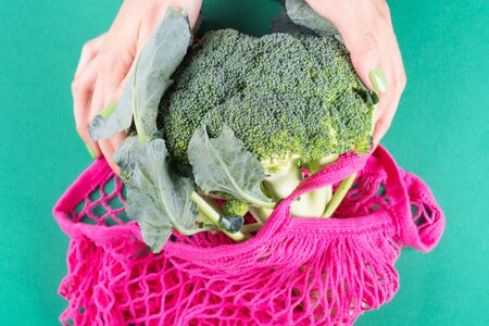 Zero waste concept. Womans hands with green manicure holding pink reusable bag with broccoli. Plastic free lifestyleの写真素材