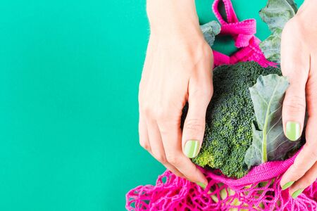 Zero waste concept. Womans hands with green manicure holding pink reusable bag with broccoli. Plastic free lifestyleの写真素材