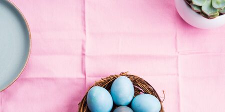 Easter festive banner for text with blue boiled eggs on pink table cloth with succulent plant. Flat lay bannerの写真素材