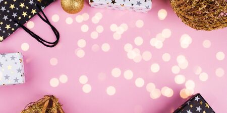 Christmas festive ornament flat lay frame with gift boxes on pink background. Golden and black
