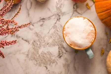 Autumn moody background with mug of latte coffee and pumpkins on marble table. Flat lay in fall colorsの写真素材