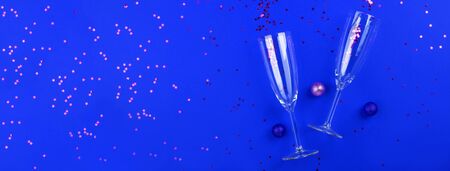 Two champagne glasses with golden star shaped confetti on classic blue color background. Celebrating new year, christmas, valentine's day concept flat layの写真素材