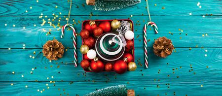 Christmas ornament in red box with pinecones and candy canes around. Creating holiday mood. Flat lay concept on traditional dark green background. Winter night feel. Bannerの写真素材