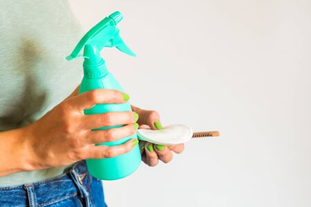Woman wearing green t-shirt holding reusable cotton pads, wooden comb and spray bottle with home made detergent. Zero waste concept in beauty routine and cleaning.の写真素材