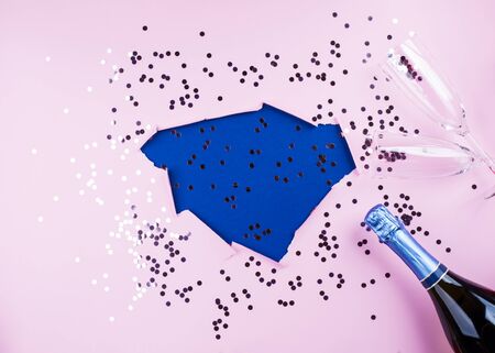 Pink paper design background with classic blue color hole and sparkling confetti, champagne bottle and glasses. Trendy festive backdropの写真素材