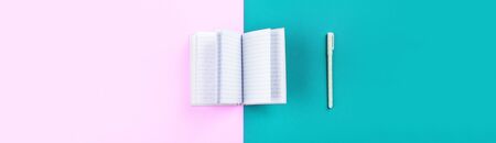 Duotone pink and blue background with open notebook and pen. Diary, planning, studying conceptの写真素材