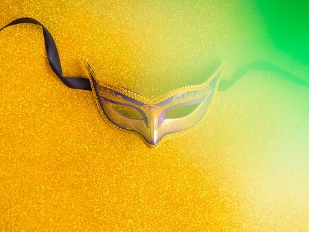 Colorful mardi gras carnival mask on golden glitter background. Festive holiday concept flat layの写真素材