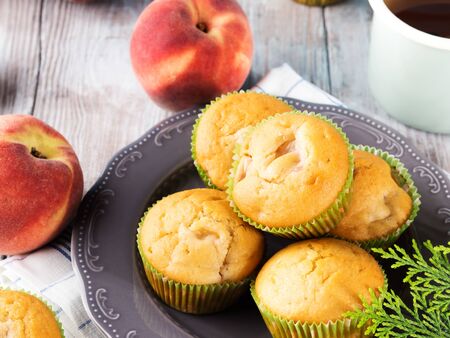 Vegan eggs free spelt wheat muffins with peaches and apples in green paper cases on checkered napkinの写真素材