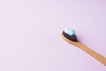 Bamboo toothbrush with blue toothpaste on pink lilac background. Personal dental hygiene concept. Zero wasteの写真素材