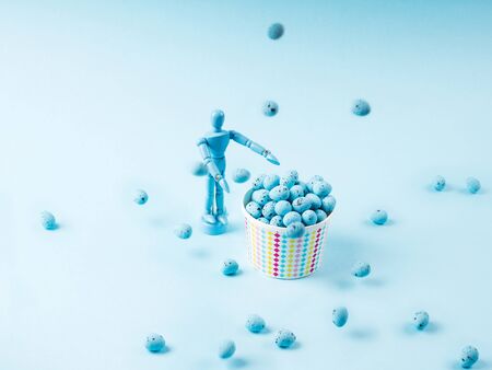 Human marionette and flying easter eggs on blue background. Holiday art concept