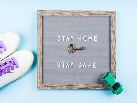 Stay home message text on letter board during covid19 pandemic. Stay safe and protect yourself from coronavirus contagion concept. Flat lay with shoes, key and toy carの写真素材