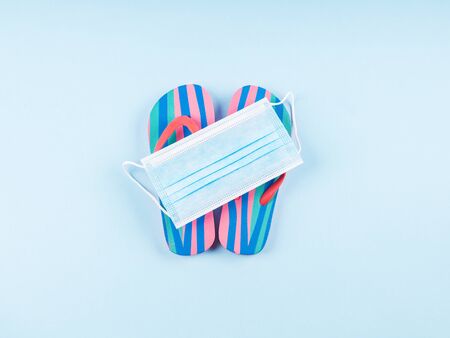 No vacation on the beach due to coronavirus covid19. Concept with colorful flip flops covered with...