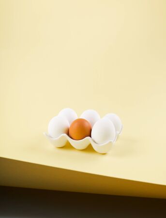 White and one brown egg on light earthy color paper background. Easter, art food creative conceptの写真素材