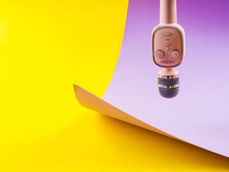 Pastel pink wireless karaoke microphone on colorful yellow and purple background. Singing, performance conceptの写真素材