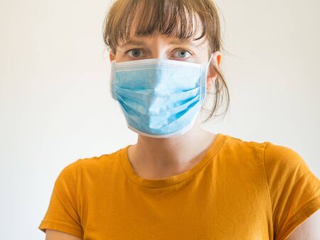 Young caucasian woman in yellow T-shirt wearing protective face mask to face virus spreading or pollution.の写真素材