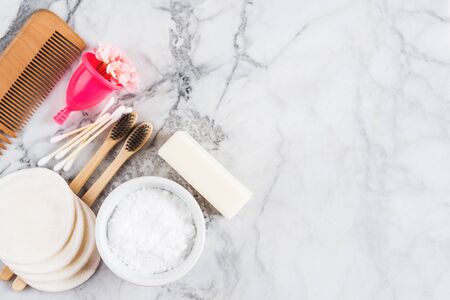 Zero waste beauty care accessories on marble table background. Wooden comb, bamboo toothbrushes,...