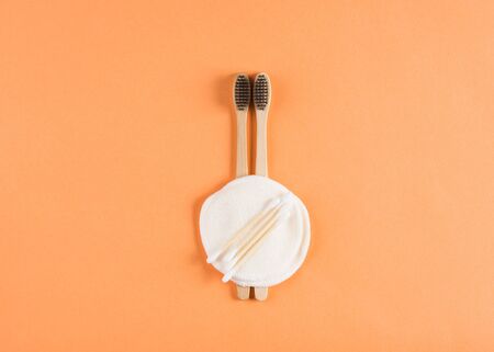 Zero waste beauty concept on orange background. Bamboo toothbrushes, reusable cotton pads, bamboo budsの写真素材