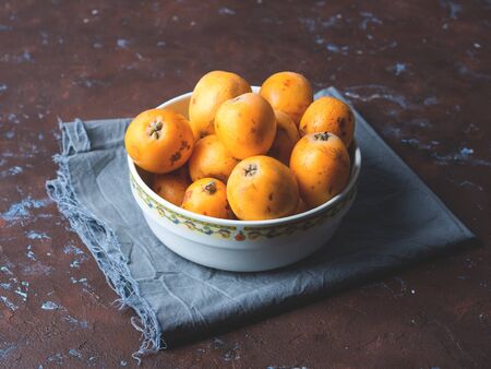 Loquat Japanese medlar fruit in bowl on dark backgroundの写真素材
