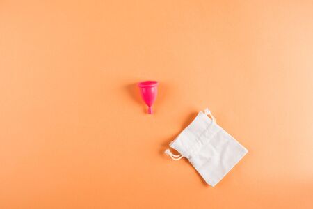 Pink menstrual cup with cotton bag, zero waste concept on orange background. Flat lay with copy spaceの写真素材